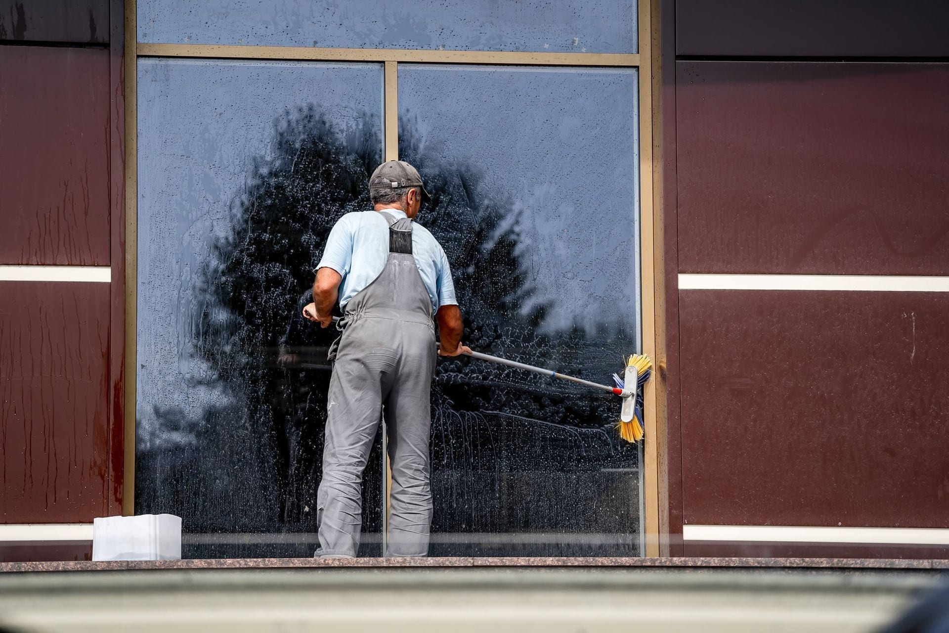 Person in protective suit spraying disinfectant in a classroom with desks and chairs.